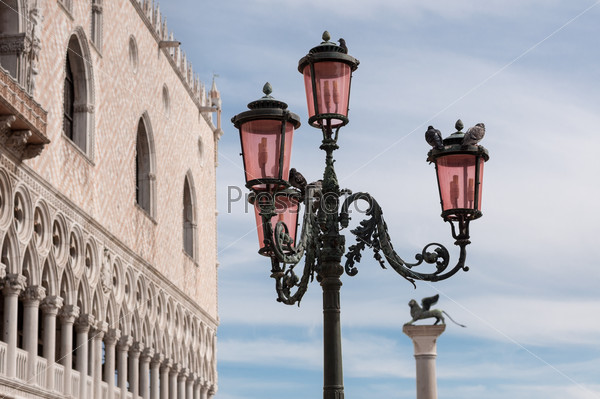 Beautiful bronze ornate lampposts in Piazza San Marco against Doge\'s Palace and column with lion in Venice, Italy.