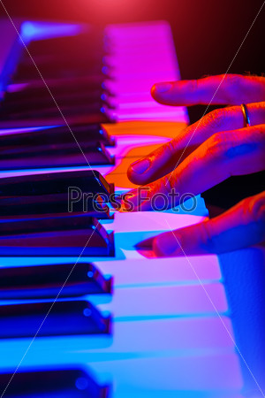 hands of musician playing keyboard in concert with shallow depth of field