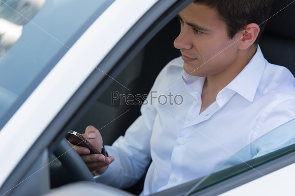 The young man behind the wheel driving car and calling phone