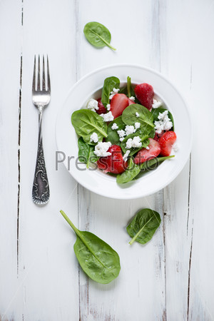 Spinach, strawberry and cheese salad, white wooden background