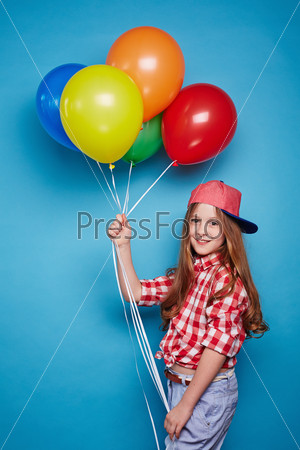 Smiling girl holding bunch of balloons in her hands