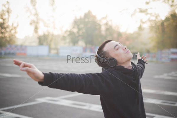 young crazy funny asian man in town outdoor lifestyle listening music with headphones - intentional backlit