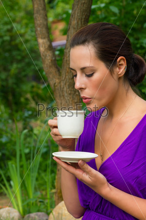 Beautiful young woman drinking coffee outdoors