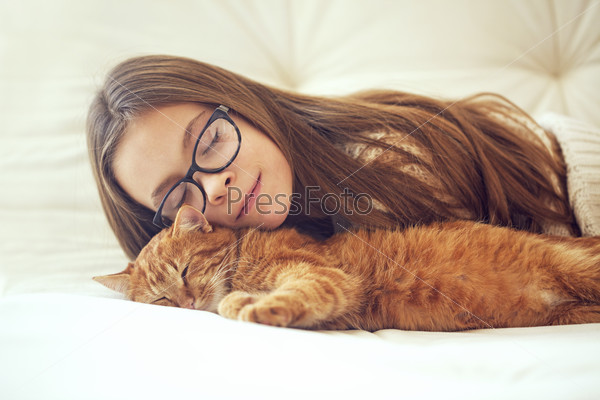 Cute ginger cat sleeps near kid girl on the sofa