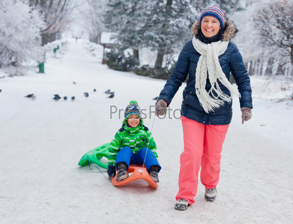 Family having fun with sled in winter park