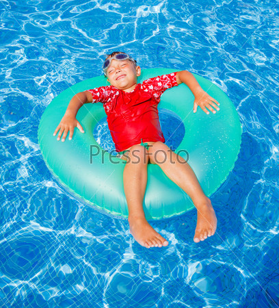 Cute little boy swims in a pool in an green life preserver