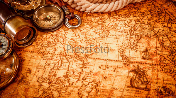 Vintage magnifying glass, compass, telescope and a pocket watch lying on an old map in 1565.