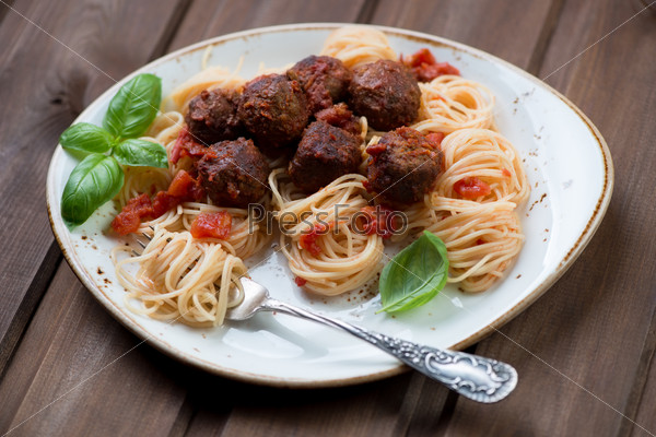 Spaghetti and meatballs over dark wooden surface, close-up