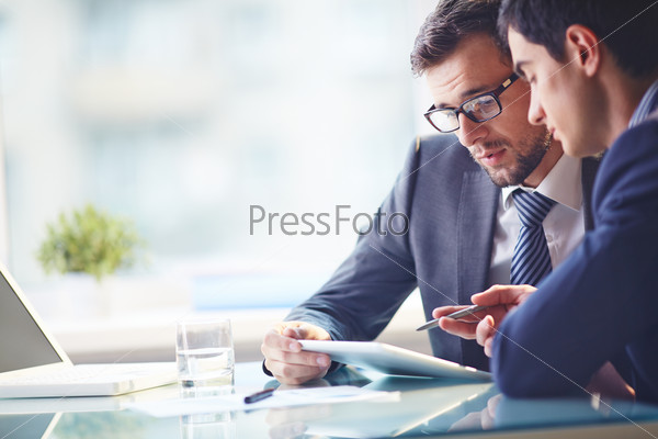 Young manager listening to his colleague explanations, stock photo