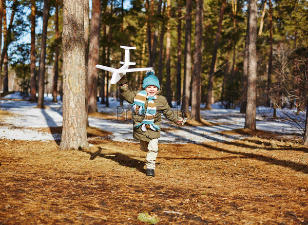 Cheerful boy running with toy airplane