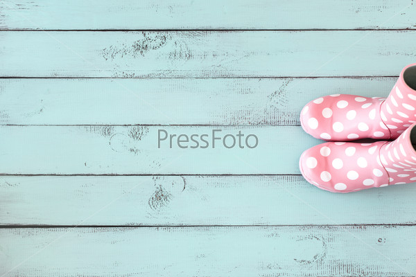 Pink polka dot rain boots on mint blue shabby chic wooden background, top view point
