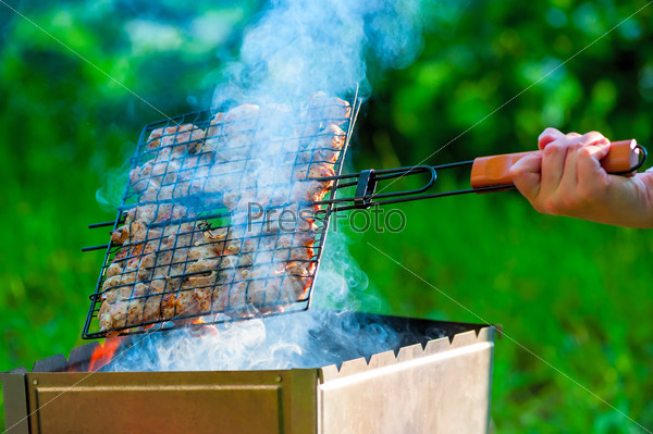 woman\'s hand turning meat on the grill