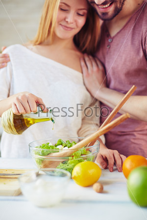 Young woman seasoning salad with olive oil