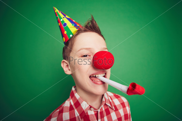 Funny kid with red nose having fun on birthday party
