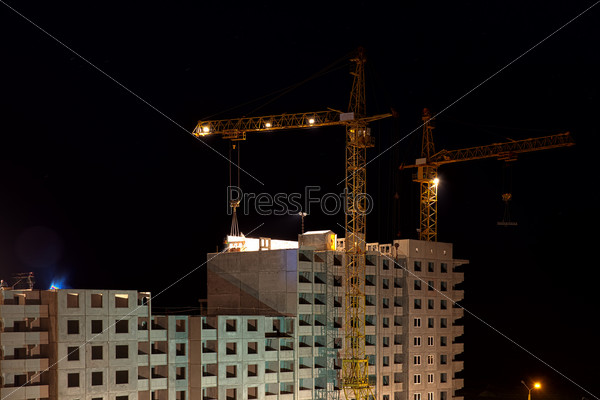 high buildings under construction with cranes at night in motion