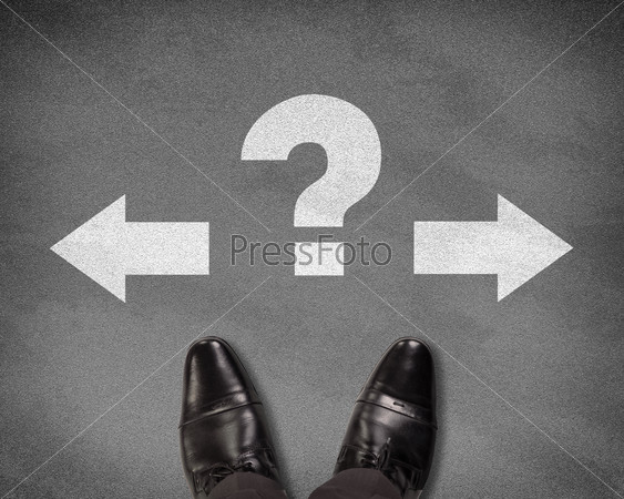 Top view of shoes standing on asphalt road with two arrows and question mark. Business concept