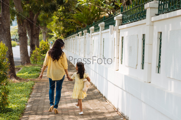 Rear view of mother and daughter walking outdoors