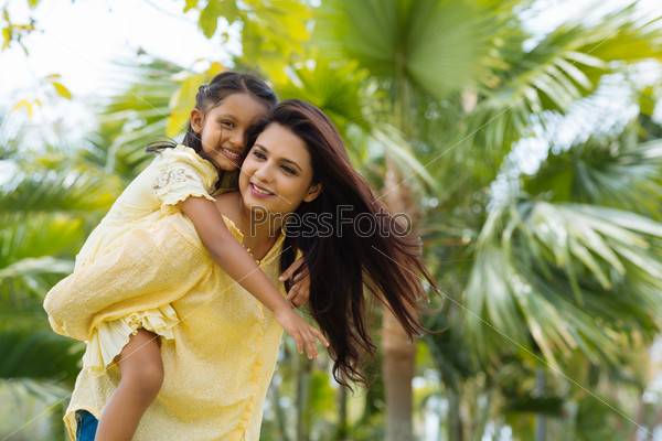 Young Indian woman giving piggyback ride to her daughter