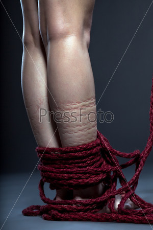 Slender woman\'s legs tied with red rope