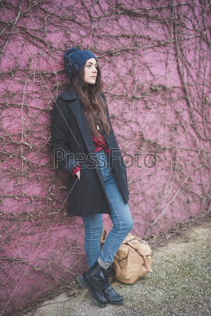 young beautiful long hair model woman living the city in winter outdoor city listening to music with headphones