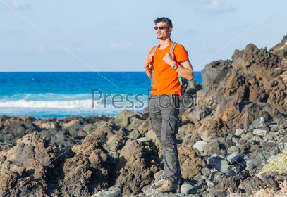 Young man in glasses with backpack. Backround blue sea