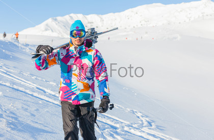 Young man with skis and a ski outfit walking in snow at winter outdoor in the Zillertal Arena, Austria