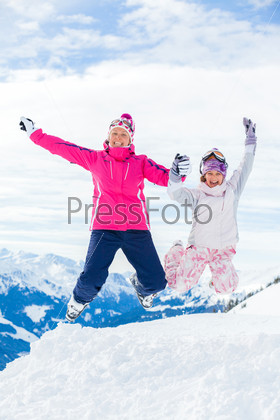Young girl with her mother a ski outfit jumping in snow at winter outdoor in the Tirol, Austria