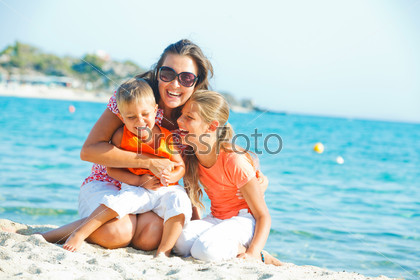 Photo of happy family laughing and looking at camera on the beach