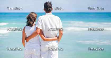 Back view of a romantic happy young couple together on the beach