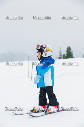 Junior skier. Little cute boy in a ski outfit rises in ski school on hill