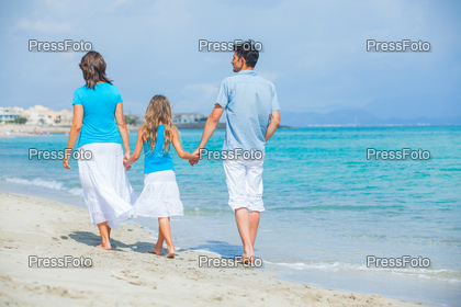 Back view of family of three having fun on tropical beach