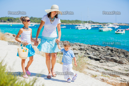 Young beautiful family of three walking along tropical beach