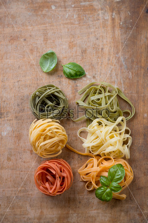 Above view of italian tricolor pasta, rustic wooden background