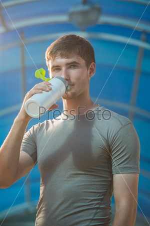Спортивный молодой человек пьет воду