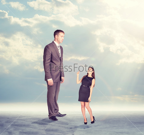 High businessman looking down at little woman in dress