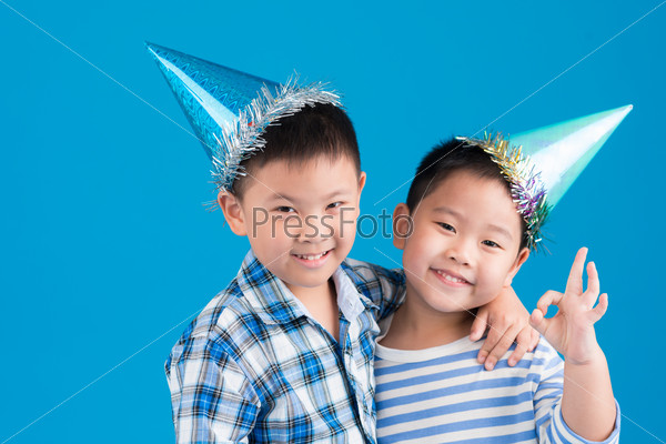 Portrait of Chinese little brothers wearing birthday hats