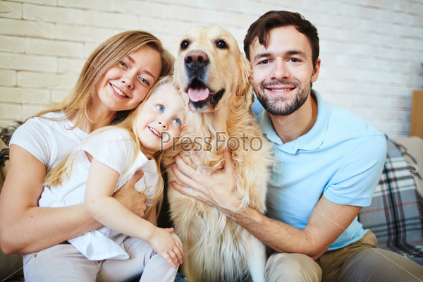 Modern family with dog looking at camera during home rest