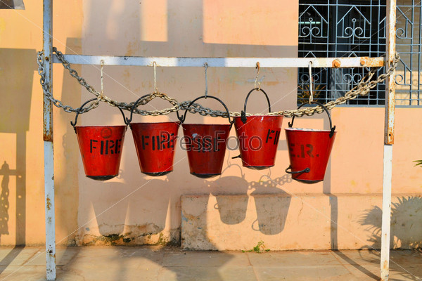 Five fire buckets hanging on a wall in India