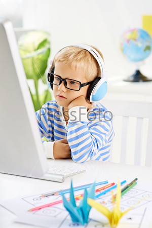 Little boy in headphones watching something on the computer