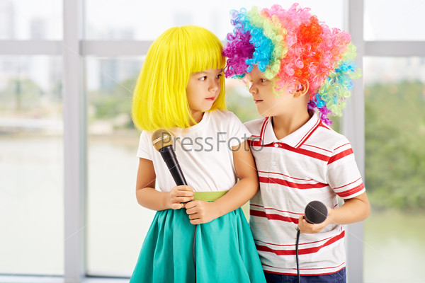 Adorable little children in colorful wigs ready to sing a song