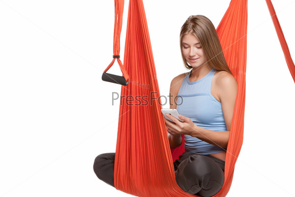Young woman sitting in hammock for anti-gravity aerial yoga