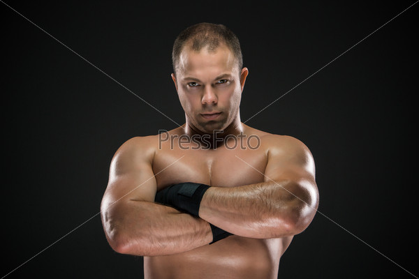studio portrait of young caucasian boxer with folded hands posing ark background