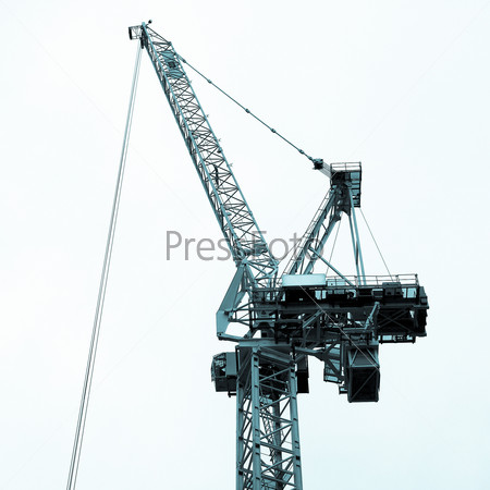 Building crane in a construction site over blue sky - cool cyanotype