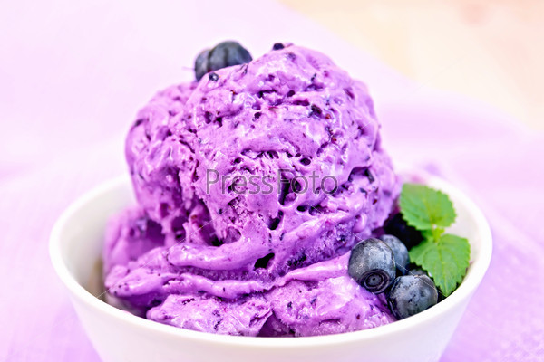 Blueberry ice cream with mint and berries in a bowl on a background of purple cloth