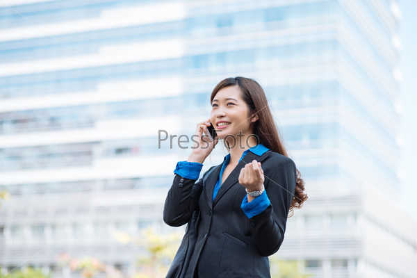 Smiling young business woman having phone talk outdoors