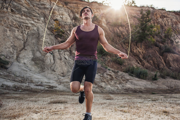 Sporty man jumping rope outdoors in the morning, stock photo