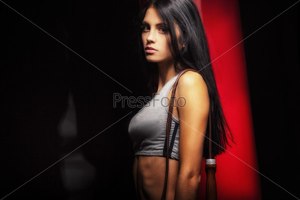 woman boxer near red punching bag over dark background