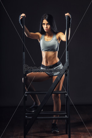 beutiful brunette woman boxer standing near ladder over dark background full length