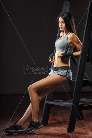 beutiful brunette woman boxer standing near ladder over dark background full length