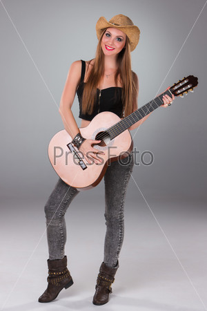 The beautiful girl in a cowboy\'s hat and acoustic guitar.